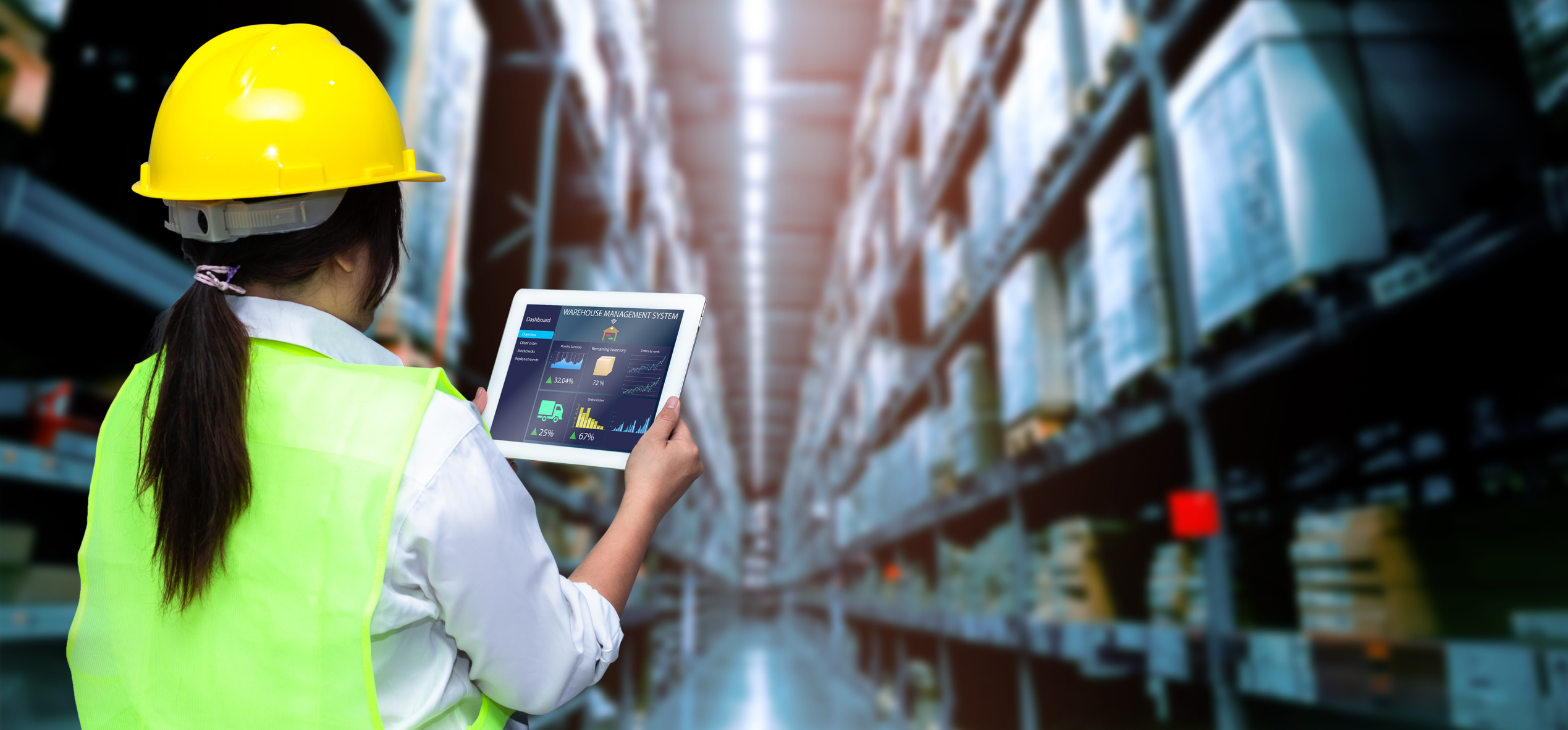 Worker holding tablet with blurred warehouse as background